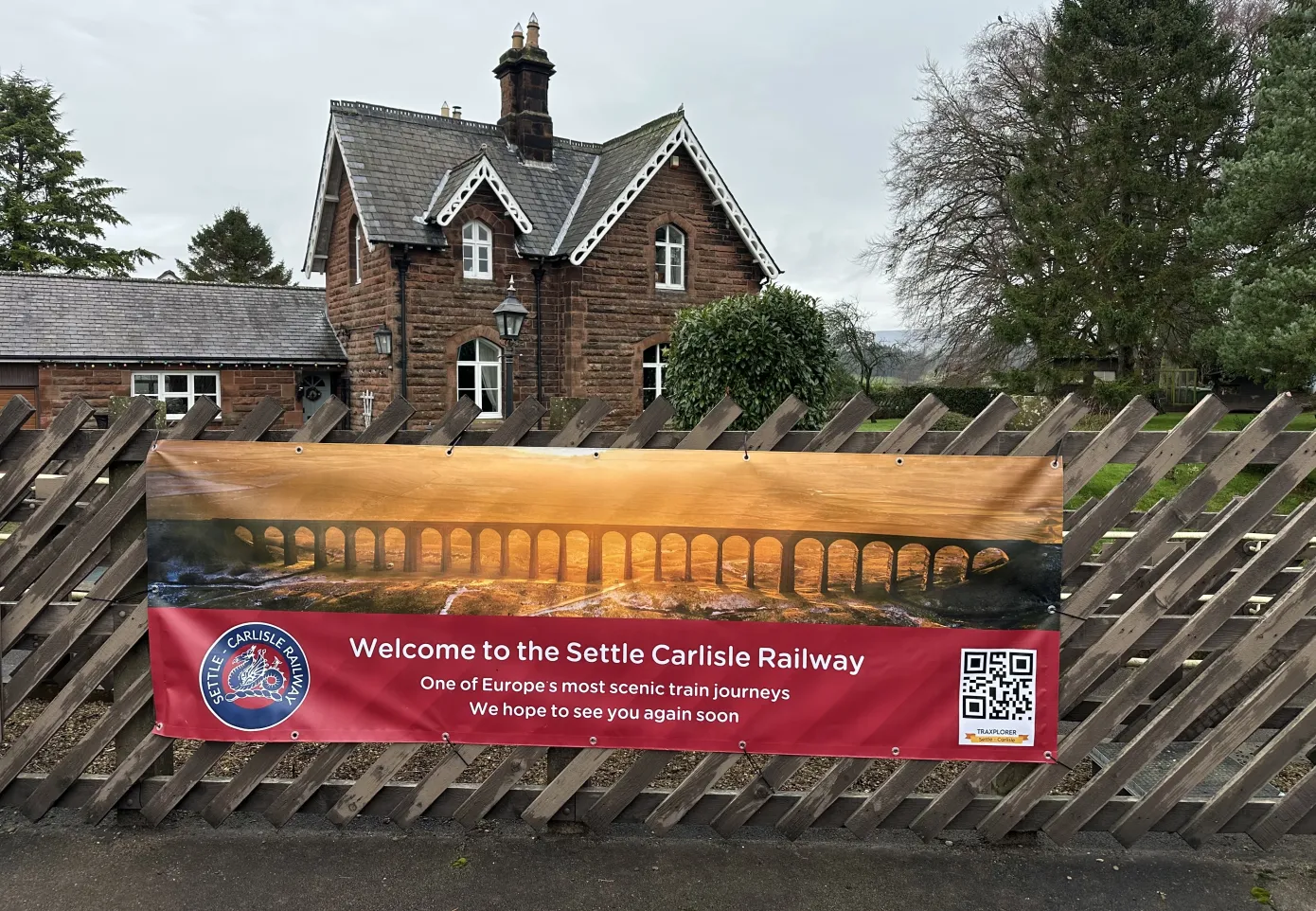 Poster infront of a railway house saying wlecome to the Settle to Carlisle line